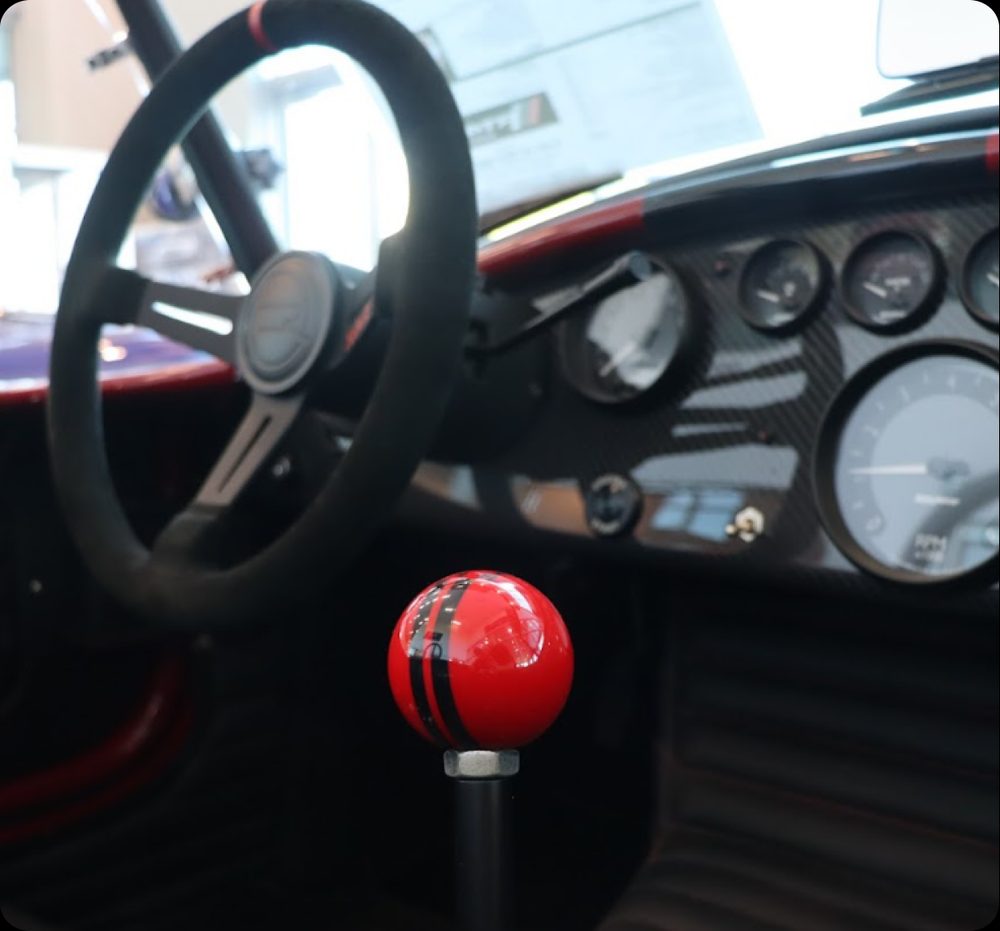 The cockpit of a finished roadster, wheel and red shift knob